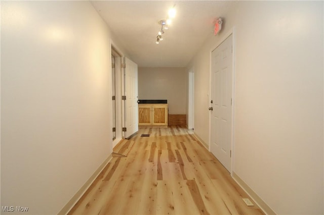 corridor featuring light wood-style flooring and baseboards