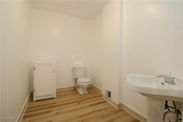 bathroom featuring toilet, wood finished floors, visible vents, and baseboards