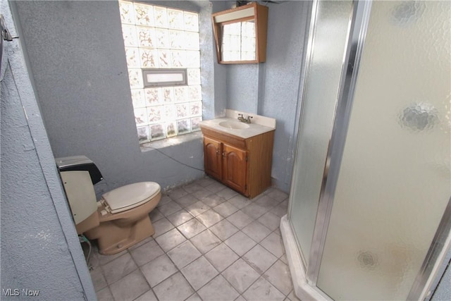 bathroom featuring a textured wall, vanity, a shower stall, and toilet