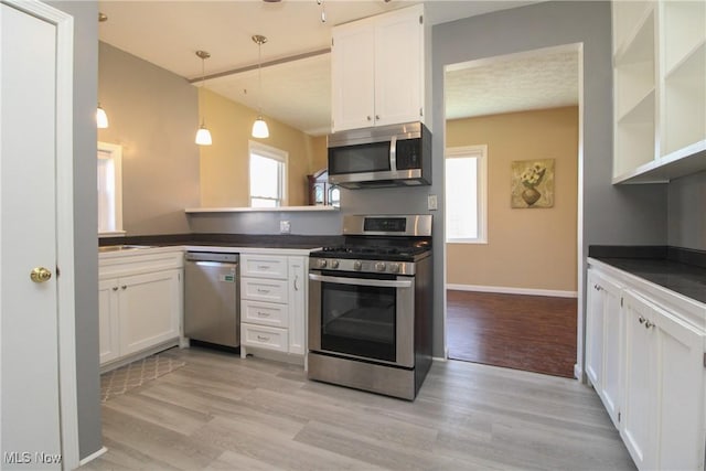 kitchen featuring light wood-type flooring, dark countertops, and appliances with stainless steel finishes