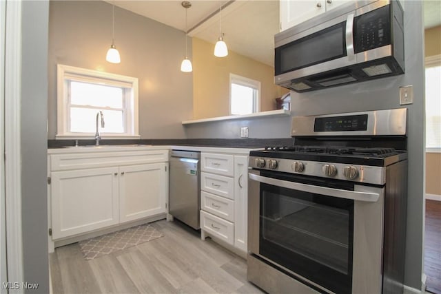 kitchen featuring a sink, stainless steel appliances, light wood-style floors, and white cabinets