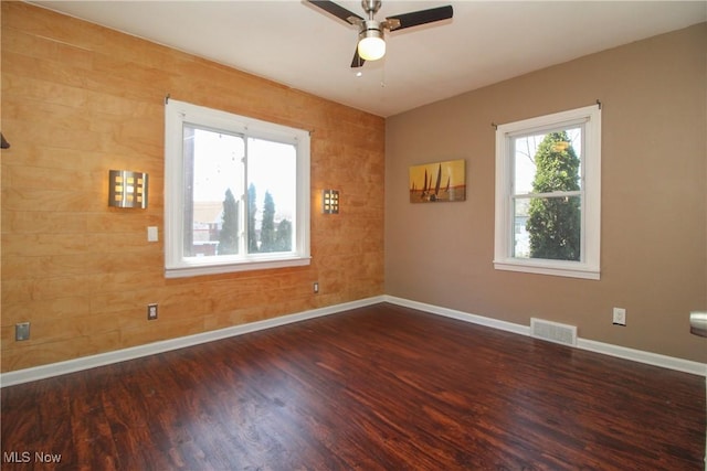 empty room with visible vents, baseboards, a ceiling fan, and wood finished floors