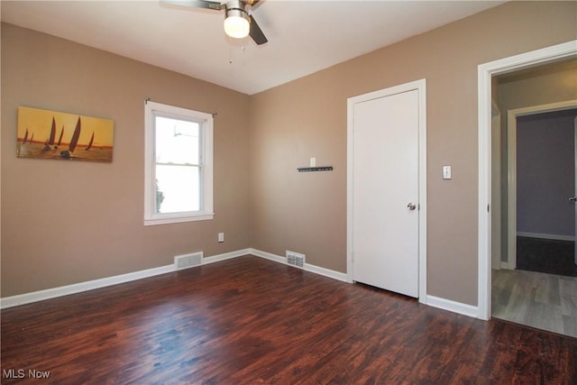 empty room featuring baseboards, wood finished floors, visible vents, and ceiling fan