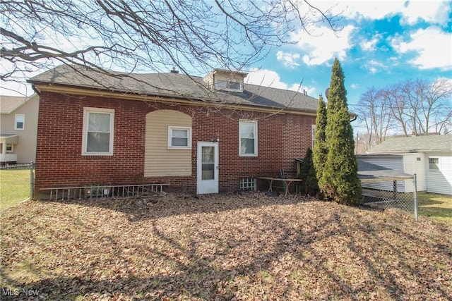 rear view of house featuring brick siding and fence