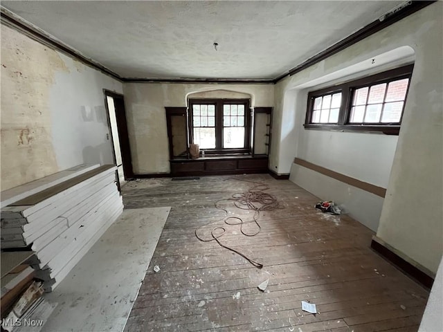 spare room featuring a healthy amount of sunlight, arched walkways, and ornamental molding