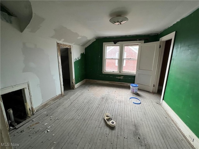 bonus room with baseboards, lofted ceiling, a premium fireplace, and hardwood / wood-style flooring