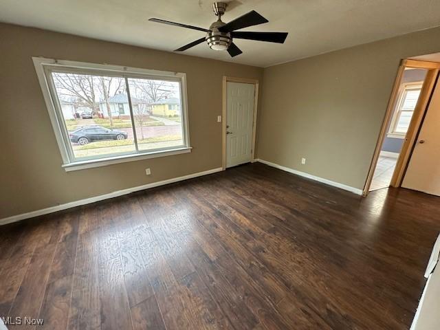 spare room featuring baseboards, dark wood-type flooring, and ceiling fan