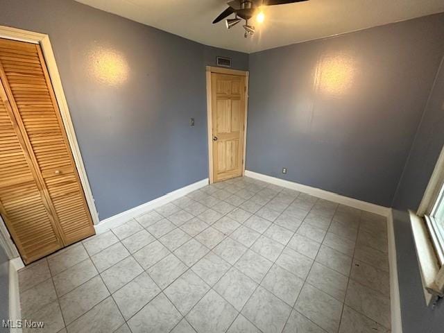 unfurnished bedroom with light tile patterned floors, a ceiling fan, visible vents, baseboards, and a closet