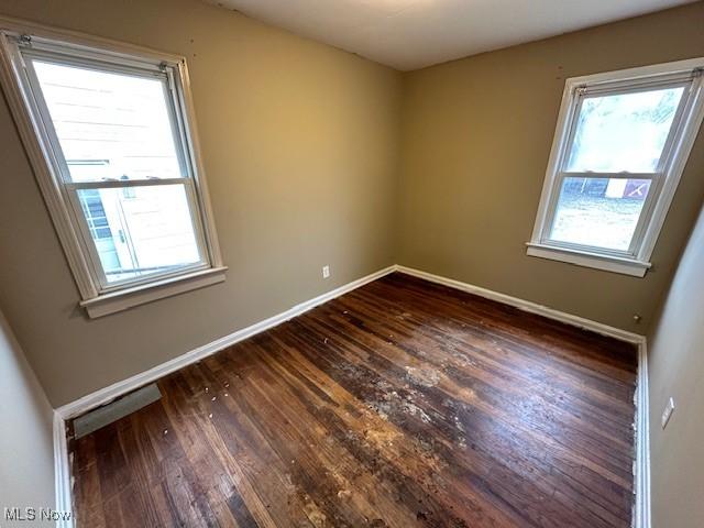 spare room with plenty of natural light, dark wood-style floors, and baseboards