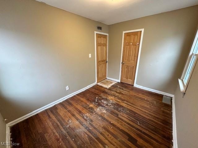 unfurnished bedroom featuring dark wood finished floors, visible vents, and baseboards