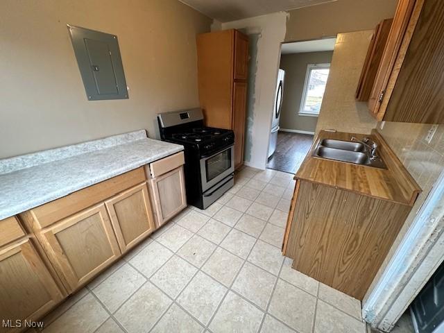 kitchen featuring light tile patterned floors, electric panel, a sink, stainless steel appliances, and light countertops