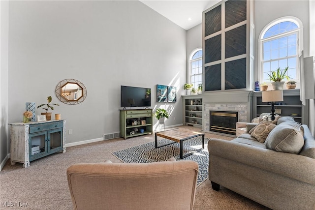 living area featuring visible vents, a large fireplace, baseboards, carpet floors, and high vaulted ceiling