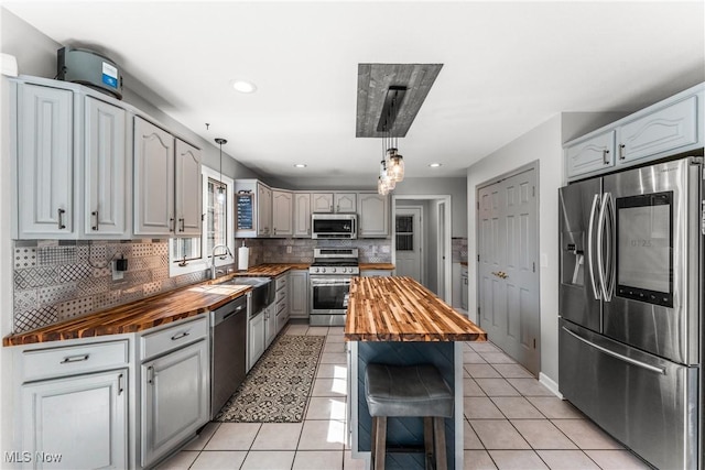 kitchen with light tile patterned floors, butcher block countertops, and appliances with stainless steel finishes