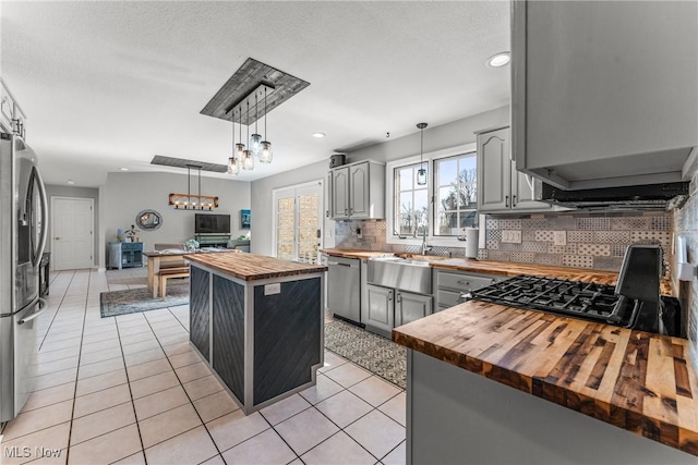 kitchen with light tile patterned flooring, gray cabinets, butcher block counters, and stainless steel appliances