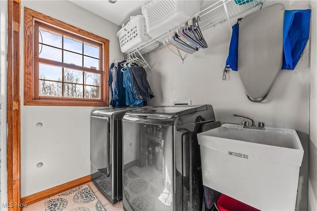 washroom with baseboards, laundry area, light tile patterned flooring, a sink, and washer and clothes dryer