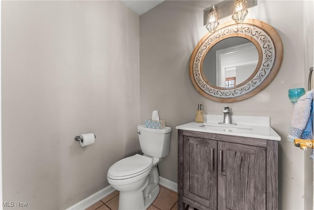 half bathroom featuring tile patterned floors, baseboards, toilet, and vanity