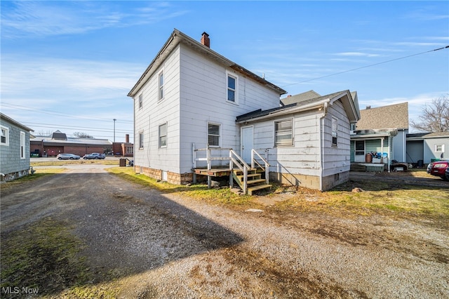 back of house featuring a chimney