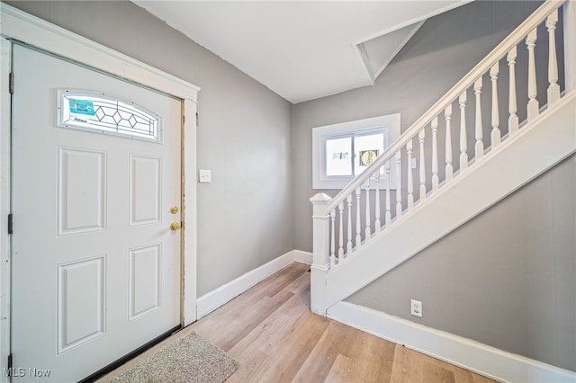 foyer entrance with stairway, wood finished floors, and baseboards