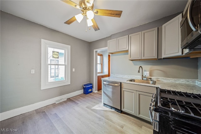 kitchen with visible vents, gray cabinetry, light countertops, stainless steel appliances, and a sink