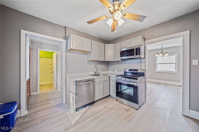 kitchen with light countertops, light wood finished floors, appliances with stainless steel finishes, and a sink