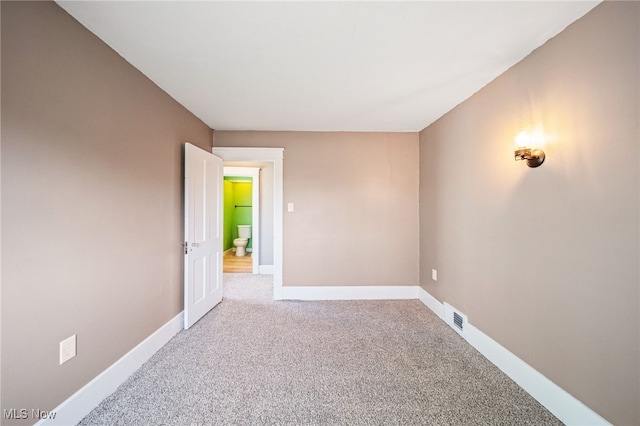 carpeted empty room featuring visible vents and baseboards