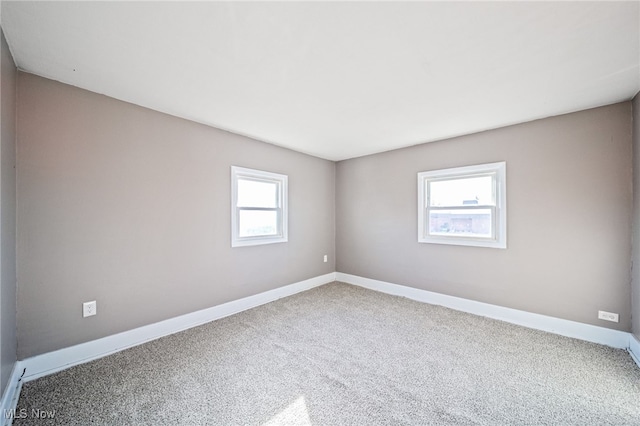 spare room with baseboards and carpet floors