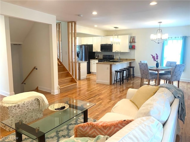 living room with recessed lighting, baseboards, a notable chandelier, and light wood-style flooring