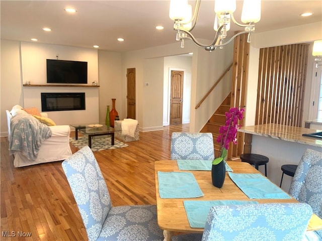 dining room featuring recessed lighting, stairs, an inviting chandelier, and wood finished floors