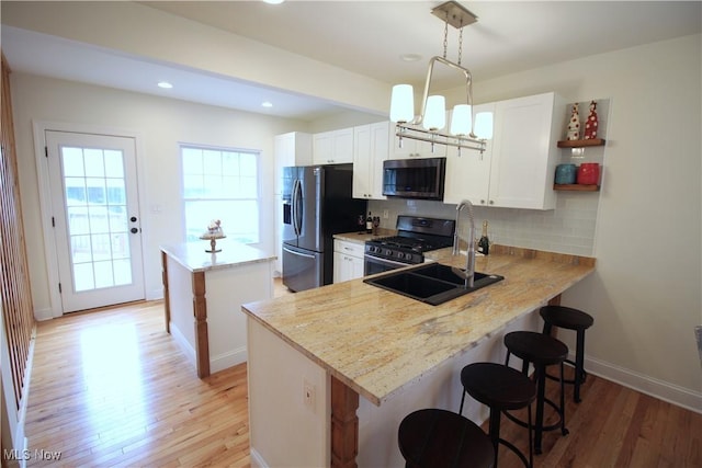 kitchen with light wood-type flooring, a sink, a center island, appliances with stainless steel finishes, and decorative backsplash