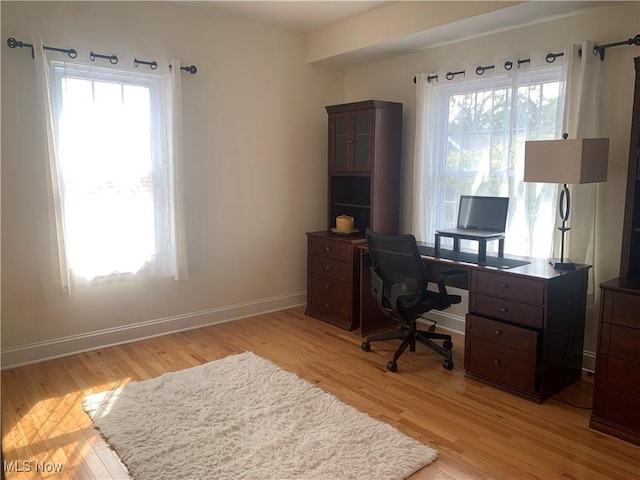 office area featuring a wealth of natural light, baseboards, and light wood finished floors