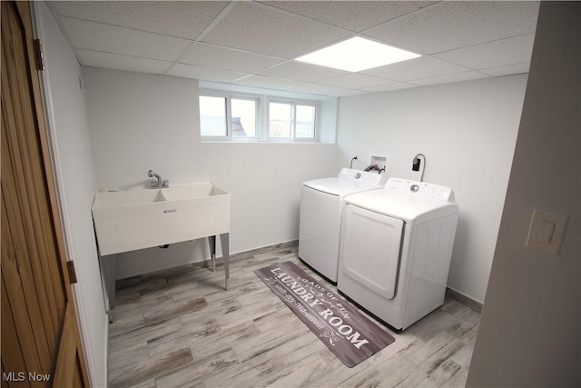 clothes washing area with laundry area, baseboards, light wood finished floors, and washing machine and clothes dryer