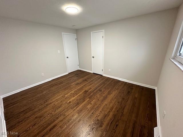 spare room with dark wood finished floors and baseboards