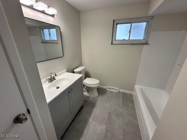 bathroom with visible vents, toilet, baseboards, a bath, and vanity