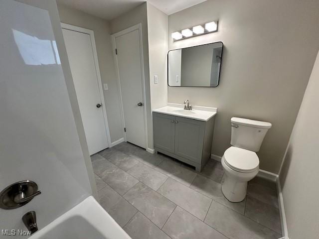 bathroom featuring vanity, toilet, a tub, and baseboards