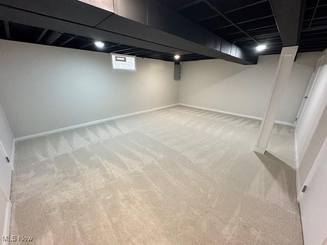 basement featuring baseboards and light carpet