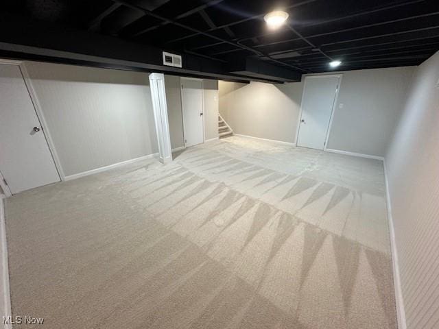 finished basement featuring stairway, baseboards, visible vents, and carpet flooring