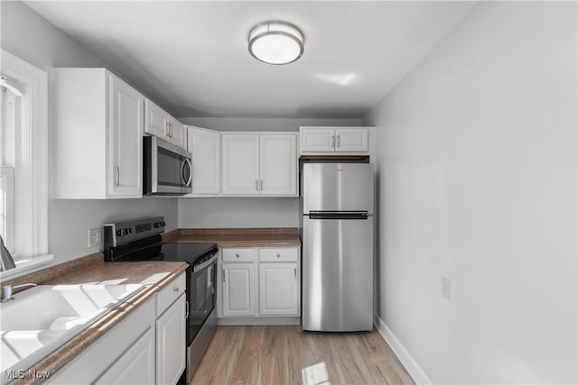 kitchen featuring white cabinets, light wood-style floors, and appliances with stainless steel finishes