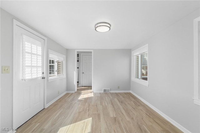 interior space featuring light wood finished floors, baseboards, visible vents, and a wealth of natural light