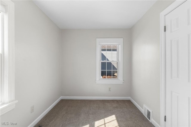 carpeted spare room featuring baseboards and visible vents