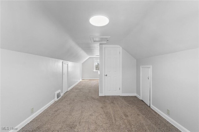 additional living space featuring vaulted ceiling, carpet flooring, baseboards, and visible vents