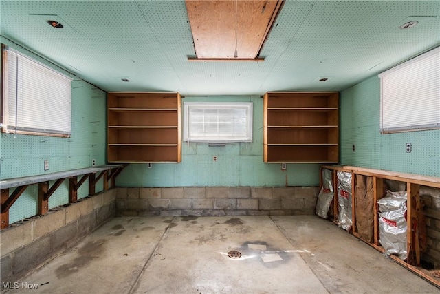 kitchen with open shelves, plenty of natural light, concrete flooring, and concrete block wall