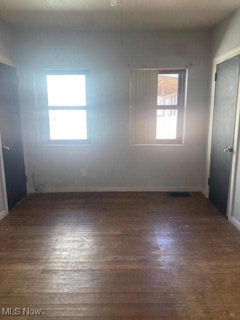 spare room featuring baseboards and wood finished floors