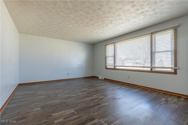 spare room with baseboards, plenty of natural light, and dark wood-style flooring