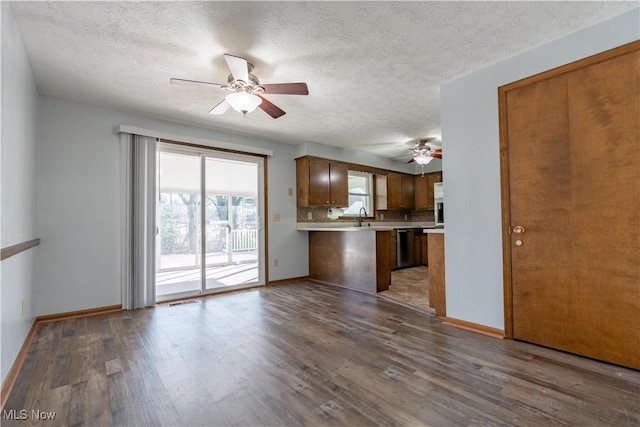 kitchen with brown cabinets, wood finished floors, a peninsula, light countertops, and ceiling fan