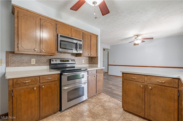 kitchen with brown cabinetry, tasteful backsplash, appliances with stainless steel finishes, and a ceiling fan