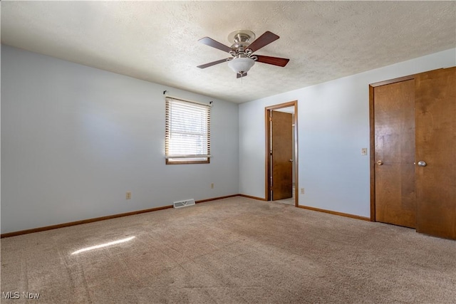 unfurnished bedroom featuring a ceiling fan, baseboards, visible vents, carpet floors, and a textured ceiling