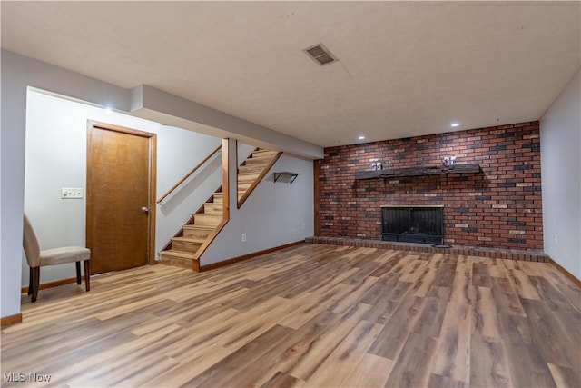 unfurnished living room featuring visible vents, baseboards, stairway, a fireplace, and wood finished floors