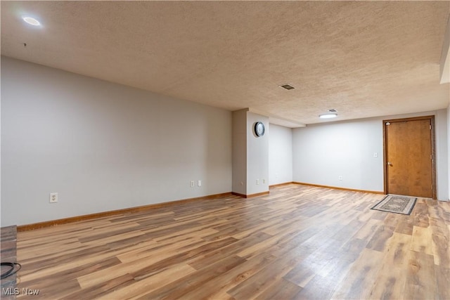 empty room with baseboards, a textured ceiling, and wood finished floors