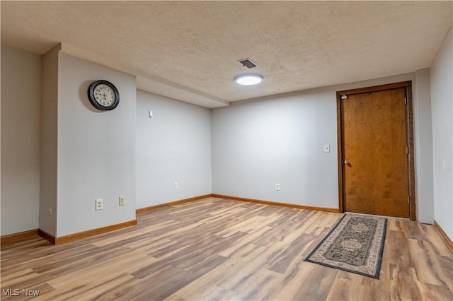 spare room with visible vents, baseboards, a textured ceiling, and wood finished floors