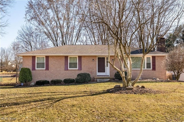 ranch-style home with brick siding, a chimney, and a front yard